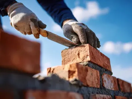 Mason setting a brick on mortar while rebuilding porch steps